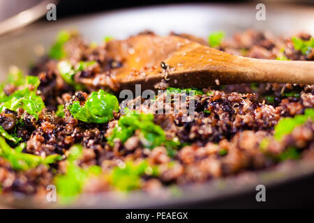 Reis in eine Schüssel geben und mit dem Holzlöffel closeup Stockfoto