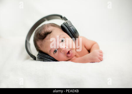 Neugeborenes Baby Hören von Musik über Kopfhörer auf einer Decke - glückliche Familie Momente Cute Stockfoto