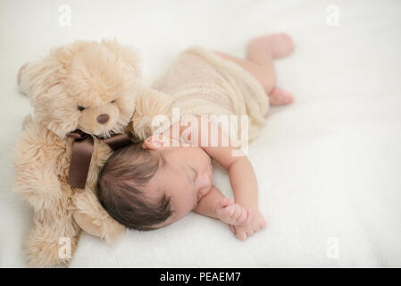 Cute Baby schläft auf einer Decke mit einem Spielzeug Teddybär - happy family Momente Stockfoto