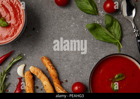 Blick von oben auf die Tomaten Suppe, Brot und Gemüse auf graue Oberfläche Stockfoto