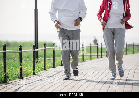 Niedrige Abschnitt Portrait von unkenntlich Active Senior Paar beim morgendlichen Lauf im Freien bei Sonnenlicht, Kopie Raum Stockfoto
