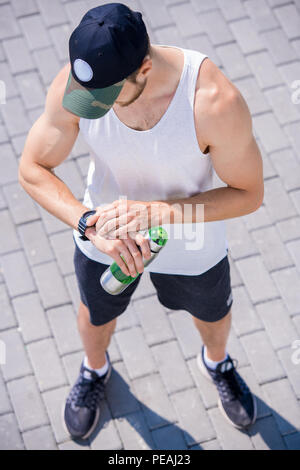 Hohen winkel Portrait von gutaussehenden jungen Mann, sportswear Kontrolle smart beobachten, während sie draußen im Park, Kopie Raum Stockfoto