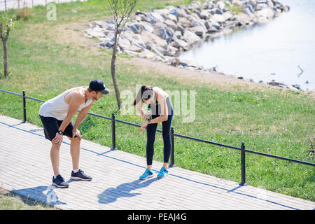 Hohen winkel Portrait von aktiven jungen Paar die Pause Atem, während draußen im Park zu fangen, kopieren Raum Stockfoto