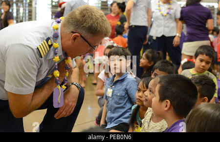 Kapitän James Jenkins, Coast Guard 14. Bezirk Stabschef, spricht mit Kindern nach einem musikalischen Urlaub Zeremonie an der Kuhio Volksschule in Honolulu, Dez. 4, 2015. Die Besatzungsmitglieder von Oahu-basierte Coast Guard Einheiten ausgeliefert, Weihnachtsgeschenke zu 300 Kinder in einem Downtown Honolulu Schule, die aus einem benachteiligten Gebiet der Insel Oahu zeichnet. (U.S. Coast Guard Foto von Petty Officer 2. Klasse Tara Molle/Freigegeben) Stockfoto