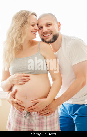 Portrait von lächelnden lachende weiße Kaukasischen jungen mittleren Alter Paare, schwangere Frau mit Mann im Zimmer umarmen, kuscheln, Lifestyle Mutterschaft anhand von quantitativen Simulatio Stockfoto