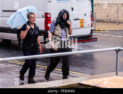 Der Mann und die Frau zu Fuß im regensturm und versucht, trocken zu halten, Harrogate, North Yorkshire, Großbritannien Stockfoto