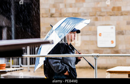 Mann zu Fuß durch Regensturm, schützende unter großer Regenschirm, Harrogate, North Yorkshire, Großbritannien Stockfoto