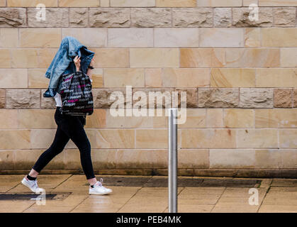 Frau zu Fuß durch Regensturm, der Kopf mit Jacke, Harrogate, North Yorkshire, Großbritannien Stockfoto