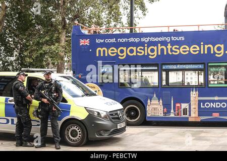 London, 14. August 2018. Eine London Sightseeing Bus fährt bewaffnete Polizei neben Westminster Bridge nach einem Terror Vorfall, wo ein Mann, der ein Auto fährt in Sicherheit Sperren außerhalb des Parlaments abgestürzt. Mehrere Menschen wurden verletzt. Credit: Claire Doherty/Alamy leben Nachrichten Stockfoto