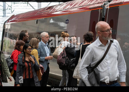 Stoke-on-Trent, Großbritannien. 14. August 2018 - Der Führer der Jeremy Corbyn in Stoke-on-Trent Bahnhof. Er hält eine Tasse Kaffee, während einer seiner Mitarbeiter trägt ein Staffordshire Töpfereien vase - ein Key Export der Stadt. Credit: Benjamin Wareing/Alamy leben Nachrichten Stockfoto