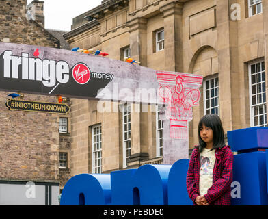 Edinburgh, Schottland, Großbritannien. 14. August 2018. Edinburgh Fringe Festival, Royal Mile, Edinburgh, Schottland, Vereinigtes Königreich. Eine junge Asiatin Uhren eine Straße Leistung Stockfoto