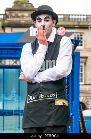 Edinburgh, Schottland, Großbritannien. 14. August 2018. Edinburgh Fringe Festival Street Performer, Royal Mile, Edinburgh, Schottland, Vereinigtes Königreich. Charlie Chaplin clown Imitator auf Stelzen weht ein Kuss Stockfoto