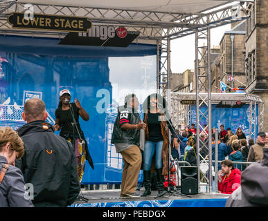 Edinburgh, Schottland, Großbritannien. 14. August 2018. Edinburgh Fringe Festival Straßenkünstler, Royal Mile, Edinburgh, Schottland, Vereinigtes Königreich. Die Fußgängerzone ist mit Phasen für Franse Darsteller gefüllt. Schwarze Sängerinnen auf der Bühne Stockfoto