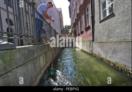 Augsburg, Deutschland. 19. Juli 2018. Klaus Wengenmayr zieht Wasser aus der Lech Kanal vor seinem Restaurant. Das Papier Künstler und Pub Besitzer produziert handgefertigte Papier aus Wasser, das er verkauft weltweit (für dpa Sommer Serie: 'Menschen am Fluss' und die KORR', Lechwasser Elefantenkot und Schafwolle ergibt exklusives Papier" vom 15.08.2018). Foto: Karl-Josef Hildenbrand/dpa/Alamy leben Nachrichten Stockfoto