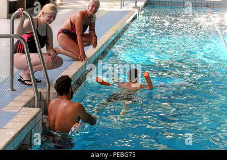 Hannover, Deutschland. 10 Aug, 2018. Schwimmlehrer Sandra Rother (links hinten) und Tochter Diandra Rother (L) einen Kurs überwachen und geben Schwimmkurse für junge Männer aus Afghanistan, Irak, Sudan und die Elfenbeinküste in der Foessebad Swimmingpool. Quelle: Holger Hollemann/dpa/Alamy leben Nachrichten Stockfoto