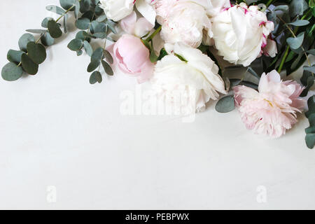 Styled Foto. Dekorative Stillleben florale Komposition. Hochzeit oder Geburtstag Blumenstrauß aus rosa und weiße Pfingstrose Blumen und Eukalyptus Filialen. Weißem Hintergrund. Flach, Ansicht von oben. Stockfoto