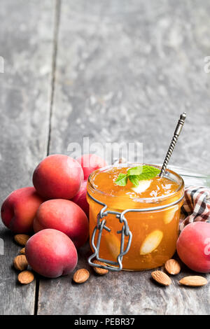 Red Aprikosenmarmelade mit Mandeln in einer klaren Glas Glas auf hölzernen Tisch Stockfoto