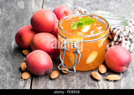 Red Aprikosenmarmelade mit Mandeln in einer klaren Glas Glas auf hölzernen Tisch Stockfoto