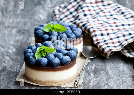 Zwei mini Schokolade Käsekuchen mit frischen Heidelbeeren auf hölzernen Tisch Stockfoto