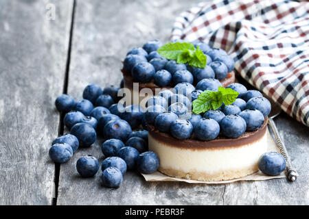 Zwei mini Schokolade Käsekuchen mit frischen Heidelbeeren auf hölzernen Tisch Stockfoto