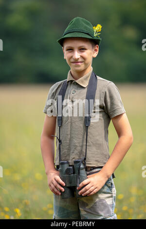 Nahaufnahme eines Jungen gekleidet wie ein Jäger mit dem Fernglas im Wald Stockfoto