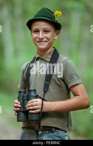 Nahaufnahme eines Jungen gekleidet wie ein Jäger mit dem Fernglas im Wald Stockfoto