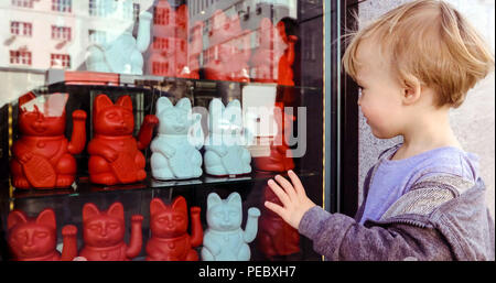 Baby Boy winkende Hand während sie Maneki Neko Stockfoto