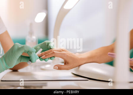 Geschickte Master der Maniküre holding Datei in Ihre Hände während der Arbeit Stockfoto