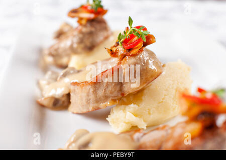 Schweinemedaillons mit Kartoffelpüree und Pilzen. Schweinefilet auf einer weißen Platte, gutes Restaurant Menü serviert. Stockfoto