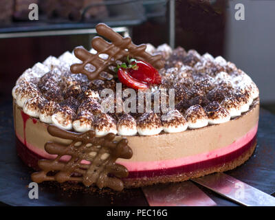 Käse-sahne-Torte mit Himbeeren, mit frischen Erdbeeren dekoriert, auf schwarzem Hintergrund Stockfoto