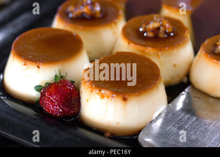 Traditionelles türkisches Dessert - Creme Caramel mit frischen Erdbeeren dekoriert, auf Schwarz Fach Stockfoto