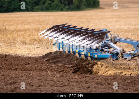 Ein Traktor mit Pflug behandelt den Boden. Stockfoto