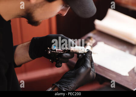 Selektiver Fokus der Tätowierer in Handschuhe mit Tattoo Maschine im Salon Stockfoto