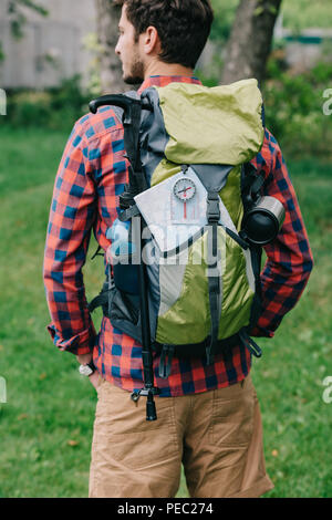 Rückansicht des jungen Mannes Reisenden mit Rucksack, Kompass und Karte Stockfoto