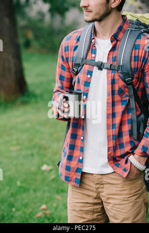 7/8 Schuß von jungen Mann mit Rucksack holding Becher Stockfoto