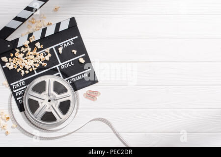 Flach mit Klappe, Bildstreifen, Popcorn und retro Kinokarten auf weißem Holz- Tischplatte angeordnet Stockfoto