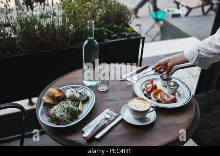 Schuß von Frau Einstellung Tisch mit leckeren Speisen im Restaurant 7/8 Stockfoto