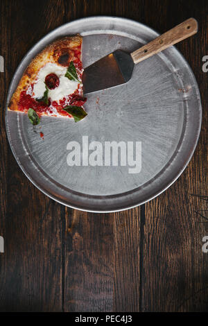 Blick von oben auf die Scheibe Pizza mit Server auf Wanne aus Metall und Holz Tisch Stockfoto