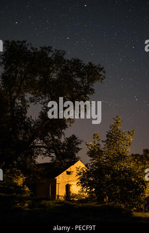 Haus in ländlicher Landschaft bei Nacht mit Sternenhimmel Stockfoto