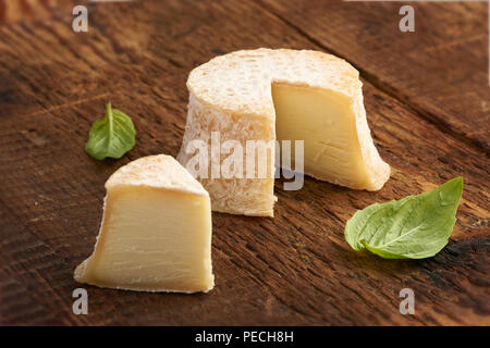 Crottin Käse mit Basilikum Blätter auf rustik Holz- Hintergrund Stockfoto