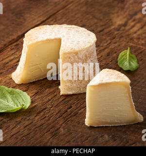 Crottin Käse mit Basilikum Blätter auf rustik Holz- Hintergrund Stockfoto