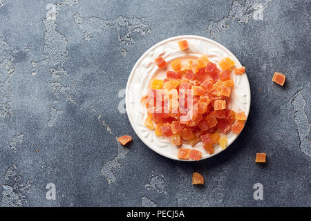 Würfel von getrockneten Aprikosen, Mangos und Papayas auf weiß palte. Kandierte Früchte über grauen Hintergrund. Stockfoto