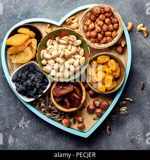 Mix getrocknete Früchte und Nüsse auf grauem Hintergrund. Blick von oben auf die SUPERFOODS. Stockfoto