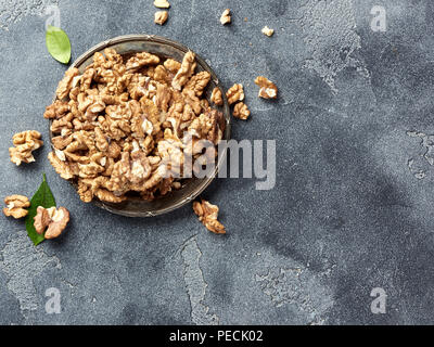 Walnusskerne an der Platte. Muttern mit grünen Blättern. Ansicht von oben. Stockfoto