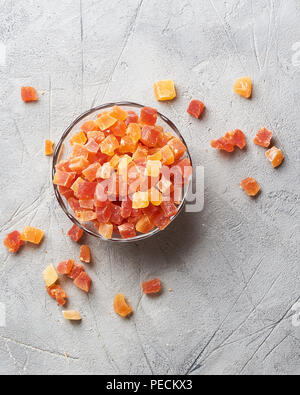 Würfel von getrockneten Aprikosen, Mangos und Papayas in der Schüssel. Kandierte Früchte über grauer Hintergrund mit kopieren. Ansicht von oben. Stockfoto