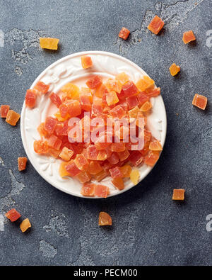 Würfel von getrockneten Aprikosen, Mangos und Papayas auf weiß palte. Kandierte Früchte über grauen Hintergrund. Stockfoto