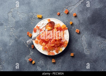 Würfel von getrockneten Aprikosen, Mangos und Papayas auf weiß palte. Kandierte Früchte über grauer Hintergrund mit kopieren. Ansicht von oben. Stockfoto