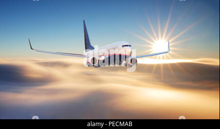 Pkw Flugzeug. Landschaft mit großen weißen Flugzeug fliegt in den roten Himmel über den Wolken und Meer bei Sonnenuntergang. Passagierflugzeug ist landi Stockfoto