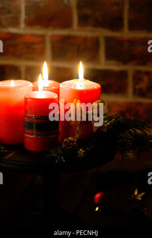 Vier rote Kerzen mit Weihnachten Dekoration in stimmungsvolles Licht. Moody. Verbindlich ist. Stockfoto