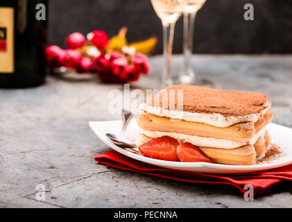 Tiramisu mit Erdbeeren und Gläser Champagner auf dem Tisch. Valentines Konzept. Stockfoto